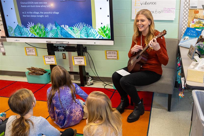 A teacher plays a ukulele for her students